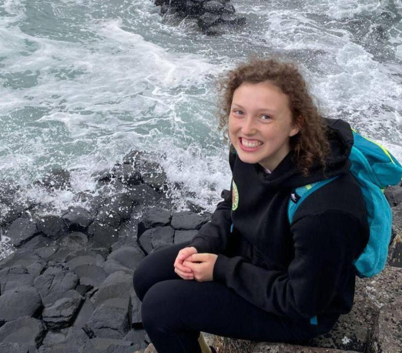 Smiling girl sitting on rocks by the ocean